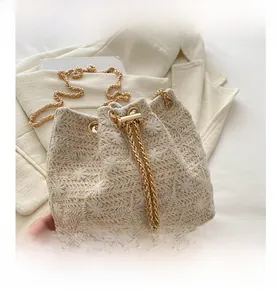 Close-up of straw bucket bag with delicate white flower embroidery and gold chain strap