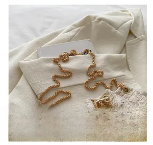 Detail of woven straw bucket bag with floral embroidery and gold metal chain strap