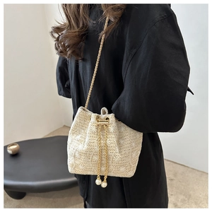 Detail of woven bucket bag with sunflower pattern, gold chain and pearl drawstrings