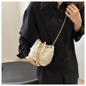 Detail of off-white woven bucket bag with floral texture, gold chain and pearl drawstring