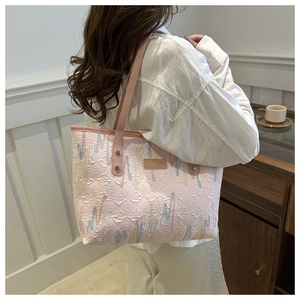 Detail showing pink quilted canvas tote with colorful wavy embroidery and brand leather patch