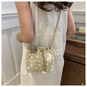 Detail view of woven straw bucket bag with delicate floral embroidery and pearl drawstring