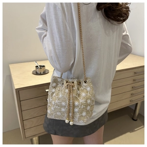 Detail of woven bucket bag featuring white floral embroidery and elegant pearl drawstring