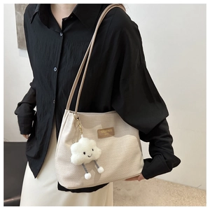 Detail of beige waffle textured tote bag with cute plush cloud charm and leather tag