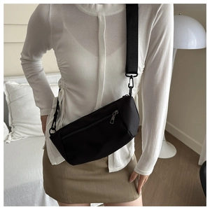 Detail of black nylon crossbody bag featuring wide adjustable strap and matte finish