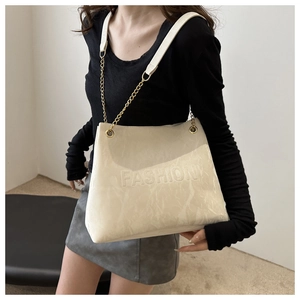Detail of cream white tote bag featuring embossed FASHION text and gold chain strap