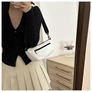 Minimalist white nylon cylindrical crossbody bag shown in a lifestyle outfit setting