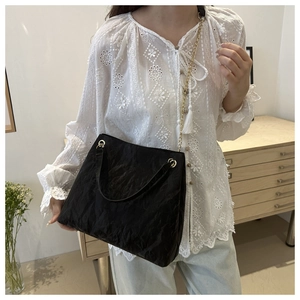 Sac à épaule plissé noir chic avec chaîne métallique dans un décor de style vie