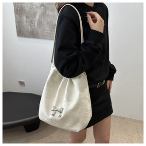Detail of soft cream PU bucket bag featuring a silver metal bow and drawstring design