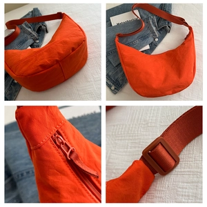 Detail van oranje nylon halve maan tas met ritssluiting en verstelbare schouderband