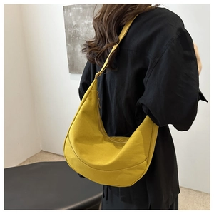 Detailweergave van de mosterdgele nylon hobo-tas met textuur en halvemaanvorm op een model