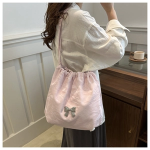 Detail of soft pink drawstring bucket bag with silver bow accent and pleated texture