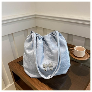 Close-up of light blue pleated bucket bag featuring a silver metal bow detail