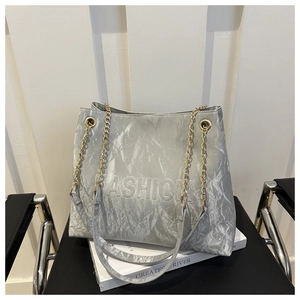 Detail of silver wrinkled texture tote bag with embossed lettering and gold chain