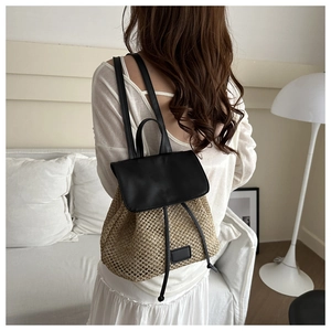 Detail of straw woven backpack with black leather flap and drawstring closure