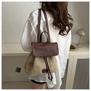 Close-up of woven straw backpack with brown leather straps shown from a back side view