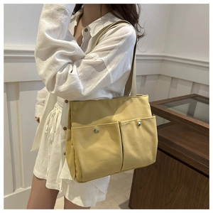 Detail of yellow canvas tote bag showing front pockets with magnetic silver buckles