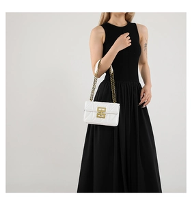 Détail d'un sac à bandoulière matelassé blanc avec fermoir doré sur robe noire
