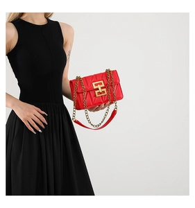 Détail du sac en cuir matelassé rouge avec boucle dorée et bandoulière chaîne sur robe noire