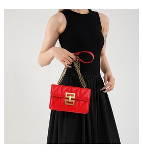 Détail du sac bandoulière matelassé rouge avec boucle dorée et bandoulière chaîne