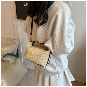 Détail du sac polochon en paille avec anses en cuir noir et fermoir en métal doré chic