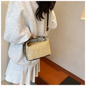 Détail du sac en paille tressée avec poignées en cuir noir et boucles en métal doré