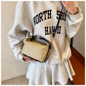 Détail du sac en paille avec lanières en cuir noir et finitions métalliques dorées