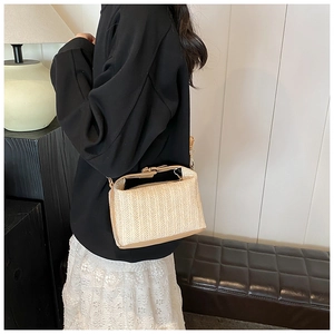 Détail d'un sac à main en paille tressée beige avec bords et bandoulière en similicuir
