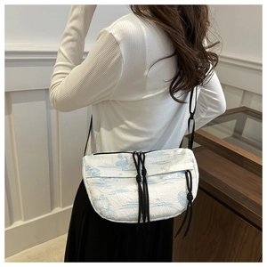 Detail of crossbody dumpling bag with blue ink landscape print and black drawstring