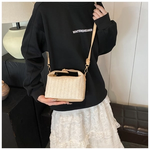 Détail du sac polochon en paille tressée beige avec boucle dorée et motif texturé unique