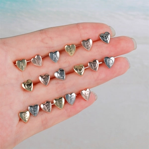 Detailed view of polished heart-shaped stud earrings in gold, silver, and rose gold finishes