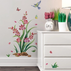 Détail de stickers muraux avec fleurs roses, feuilles vertes et papillons sur un mur blanc