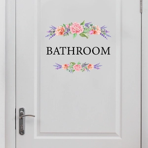 Close-up of floral wall decal with bathroom text on a white wooden door with silver handle