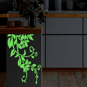 Glow-in-the-dark floral vine sticker illuminating a kitchen cabinet in dim lighting