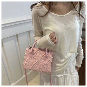 Detailed texture of pink fringe denim mini bag with distressed surface and top handle
