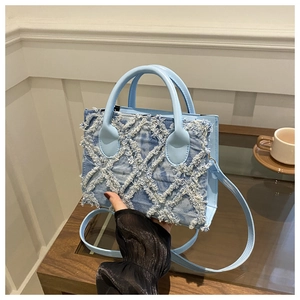 Close-up of light blue denim handbag featuring distressed frayed woven diamond texture