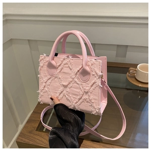 Close-up of pink denim handbag featuring raw-edge quilted patterns and gold metal buckles