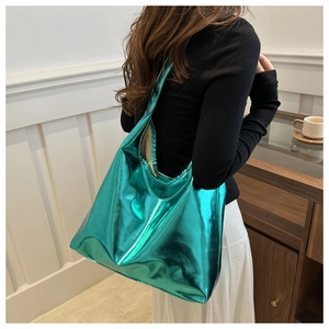 Detailed view of glossy metallic turquoise PU leather tote bag worn by a model