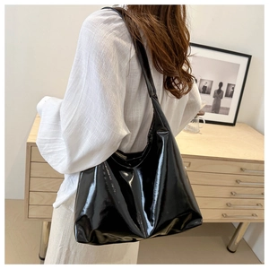 Close-up of the glossy black PU leather tote bag showing reflective finish and wide strap
