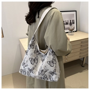 Lace embroidery tote with butterfly prints and fringe trim shown on a model's shoulder