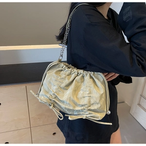 Detail of light green pleated bucket bag with bow accents and metal chain strap