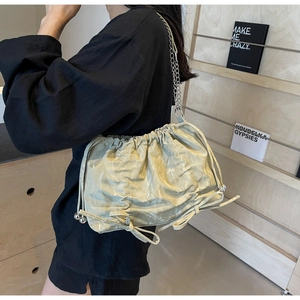 Close-up of sage green pleated bucket bag with silver chain strap and drawstring detail