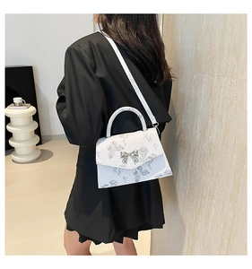Detail of white floral butterfly crossbody bag with silver bow buckle on model