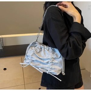 Light blue pleated bucket bag with silver chain strap shown in a lifestyle setting