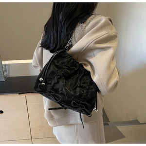 Detail of black pleated tote bag with silver chain strap and drawstring metal bead accents