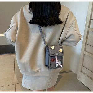 Detail of grey crossbody bag with colorful heart patches and stylish pink ribbon decoration