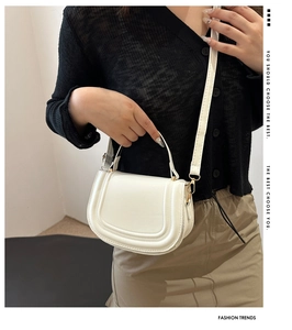 Detail of white saddle bag with fine stitching, gold hardware and slim strap