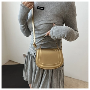 Chic gold metallic saddle handbag with U-shape silhouette and adjustable shoulder strap