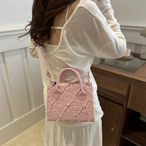 Pink frayed denim crossbody bag with quilted texture shown on a female model