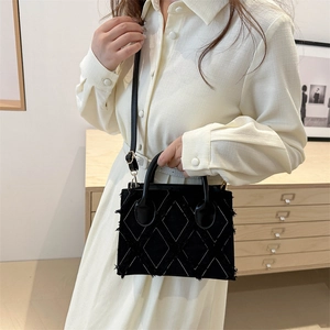 Denim crossbody bag with white diamond stitching and frayed edges shown in a home setting
